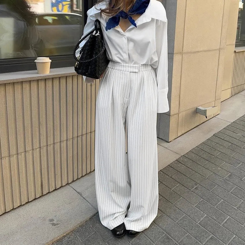 White striped wide-leg women's trousers with a front zipper on a hanger.