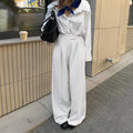 White striped wide-leg women's trousers with a front zipper on a hanger.