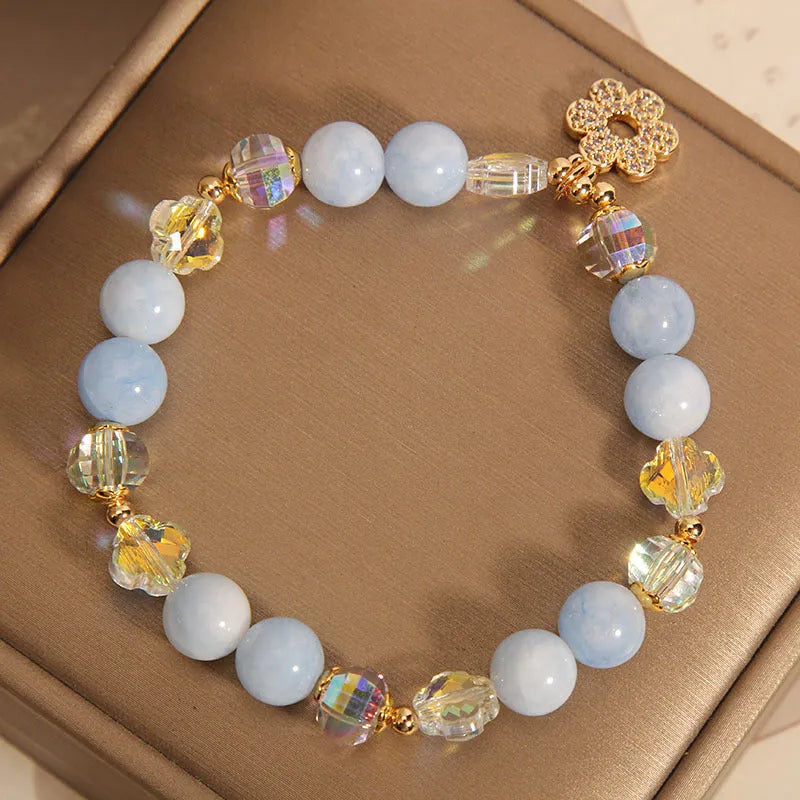 Women's aquamarine crystal four-leaf clover bracelet with pearl accents on a silver chain.