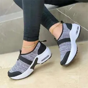 Women's white mesh flat sneakers with a rubber sole shown from the side.