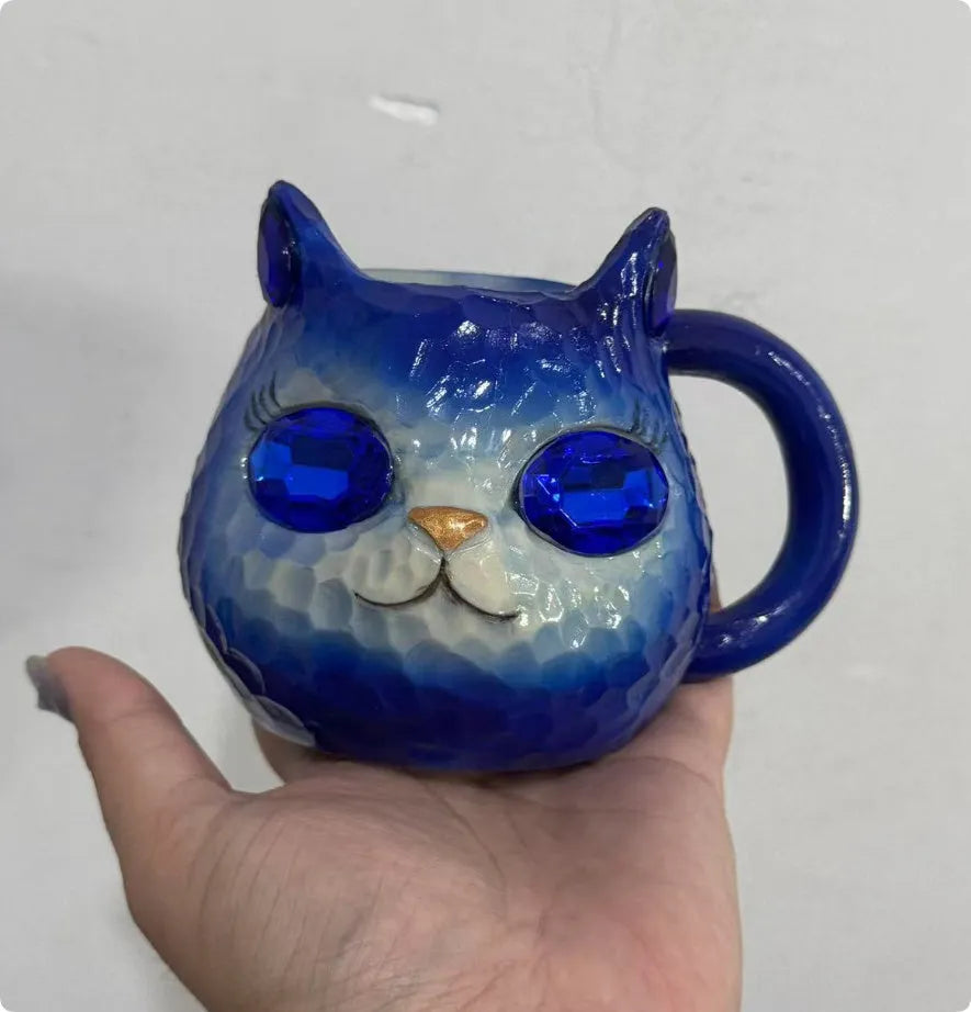 Coloured resin cat cup decoration in purple, green, blue, or pink on a shelf.