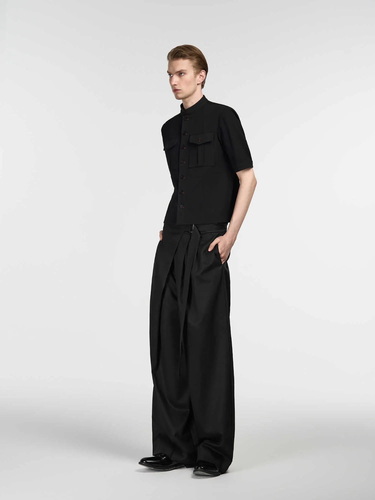 Black straight-leg trousers with a single pleat and adjustable waistband on a hanger
