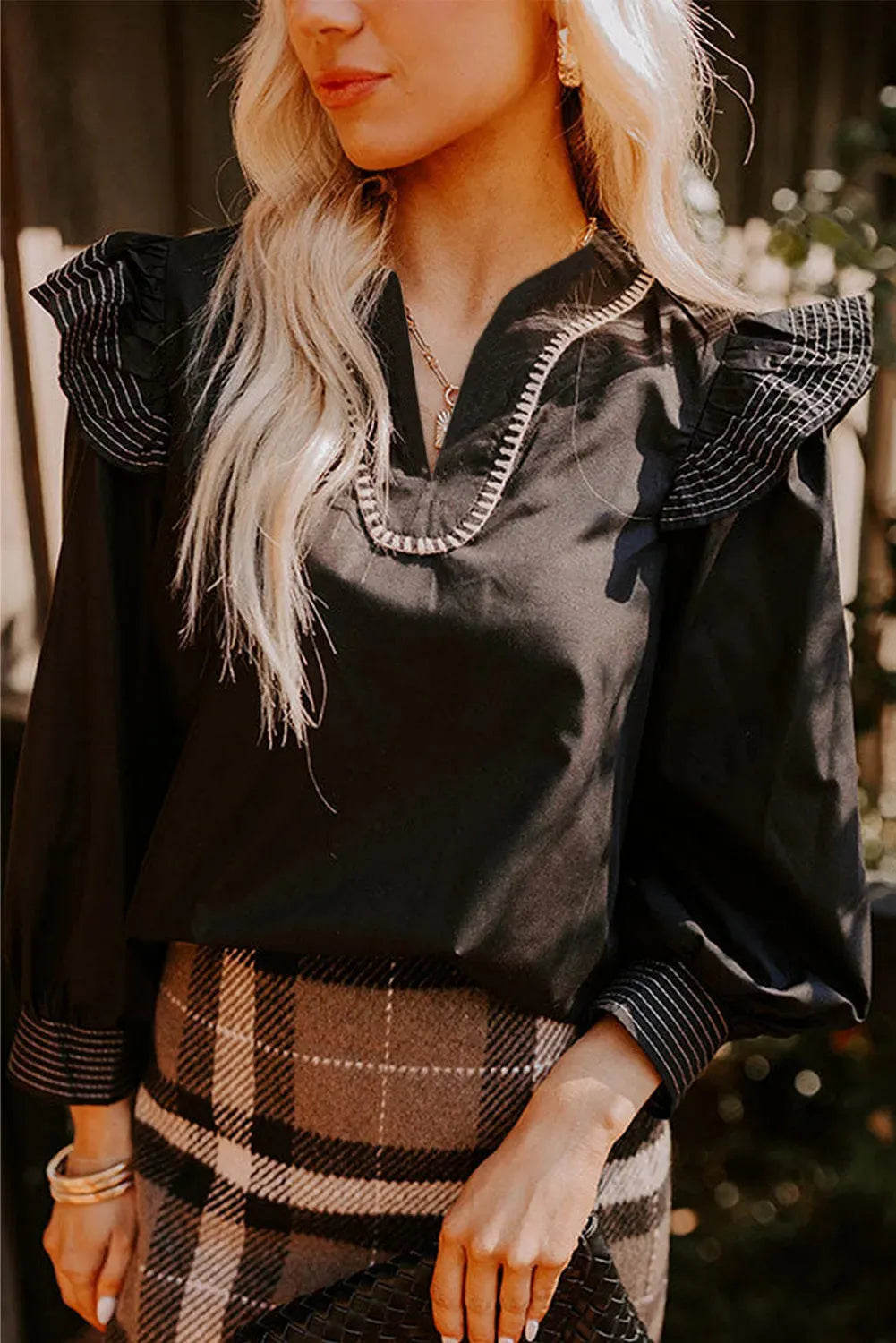 Black women's blouse with V-neck, long ruffle sleeves, and contrast stitch detail.