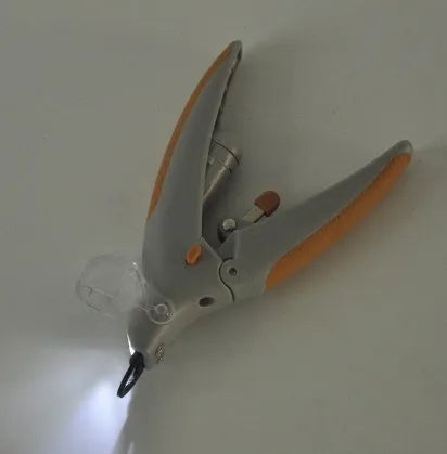 White plastic dog nail clipper with built-in LED light and red guide line on a blister card.