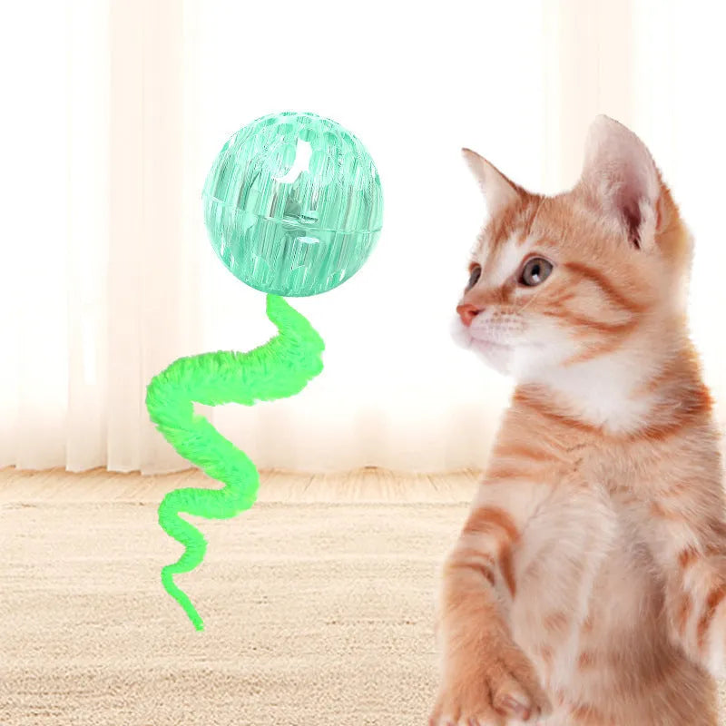Green interactive cat toy featuring a bouncy ball with a long plush tail on a wooden floor.