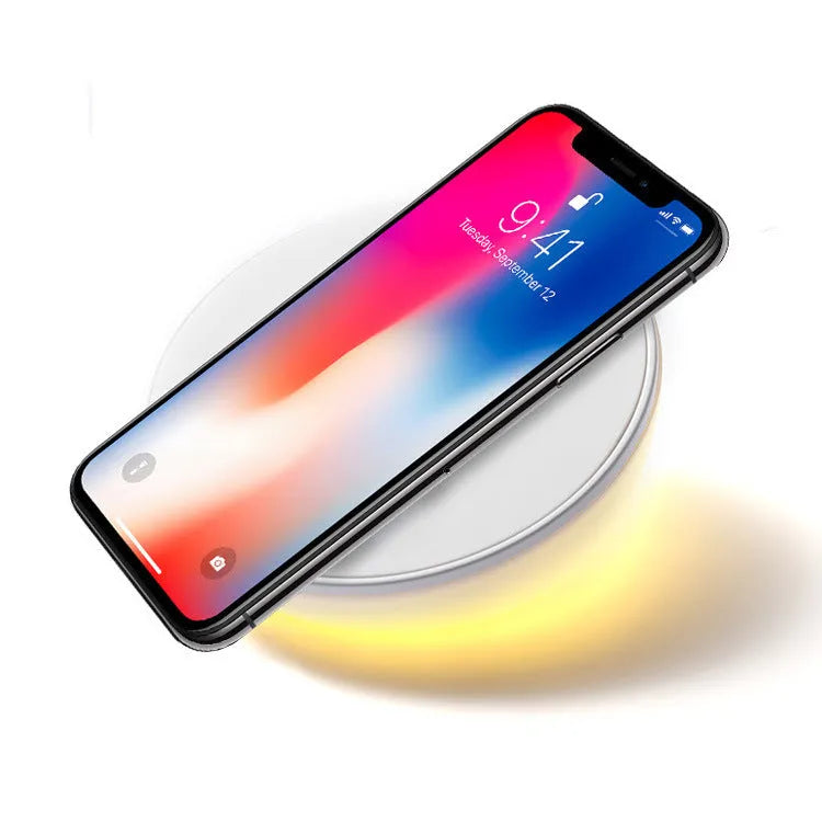White wireless charger with digital clock display and night light feature on a bedside table