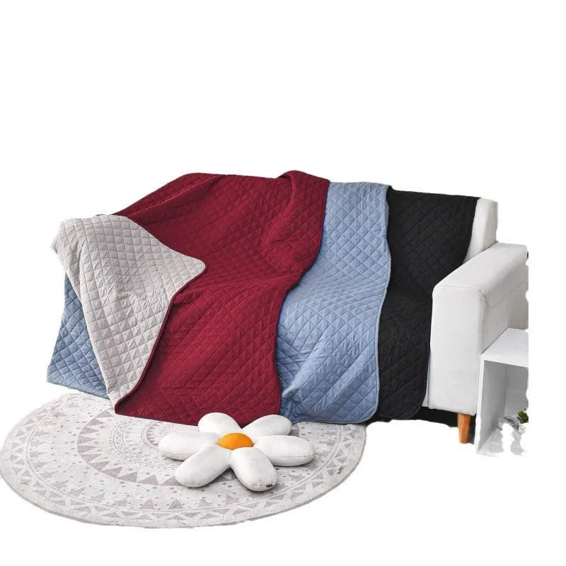 Reversible waterproof dog blanket laid flat on a sofa, showing two colour options.