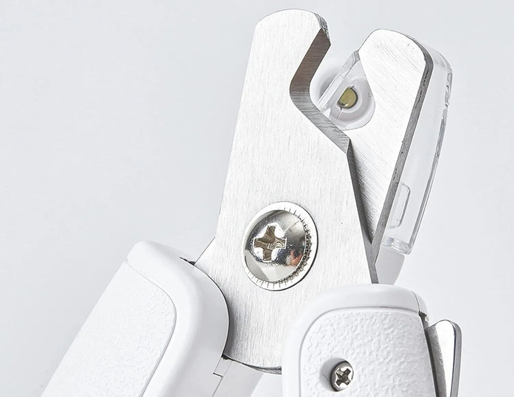 White pet nail clippers with LED light, anti-splash guard, and built-in file on a grey surface