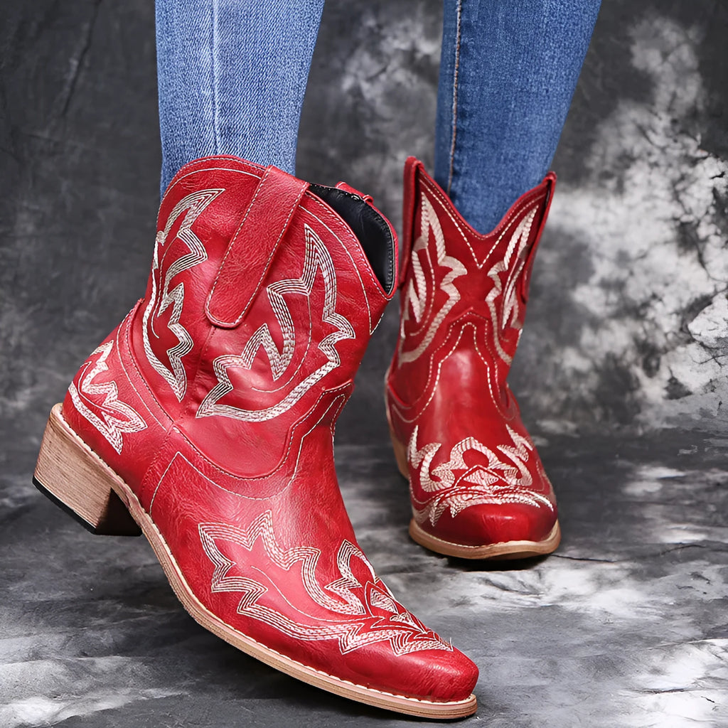 Women's blue embroidered cowboy boots with low wedge heel and pointed toe on a white background.