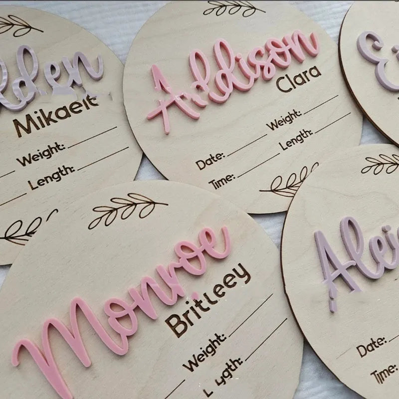 Square wooden newborn name label showing baby birth information and surname on a plywood plaque.