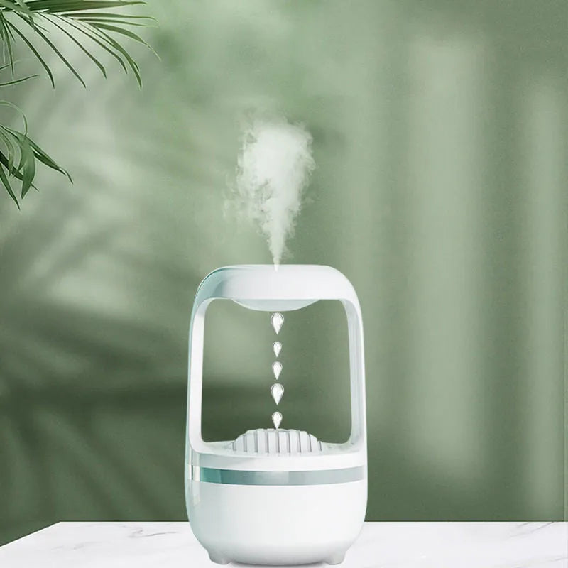 White anti-gravity humidifier on a desk showing water droplets in mid-air backflow, with USB cable.