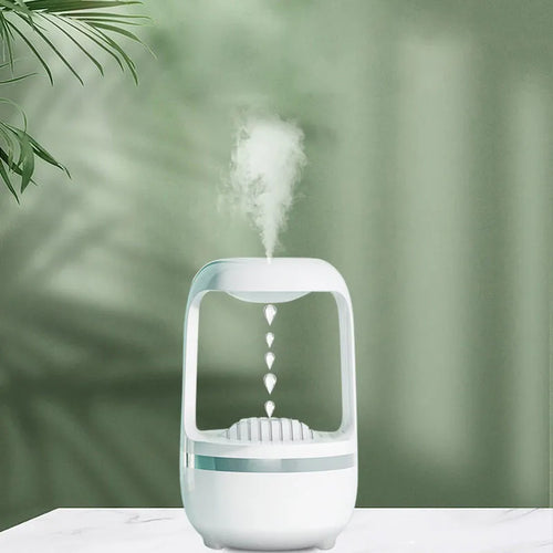 White anti-gravity humidifier on a desk showing water droplets in mid-air backflow, with USB cable.