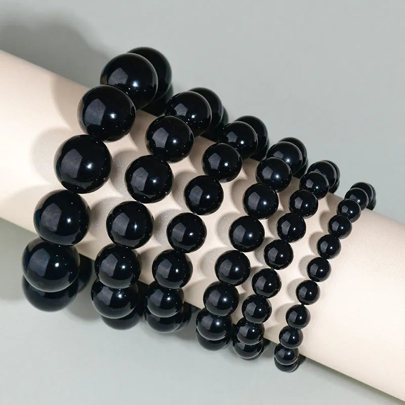 Hand-woven round obsidian bead bracelet in multiple colour options on a wrist.