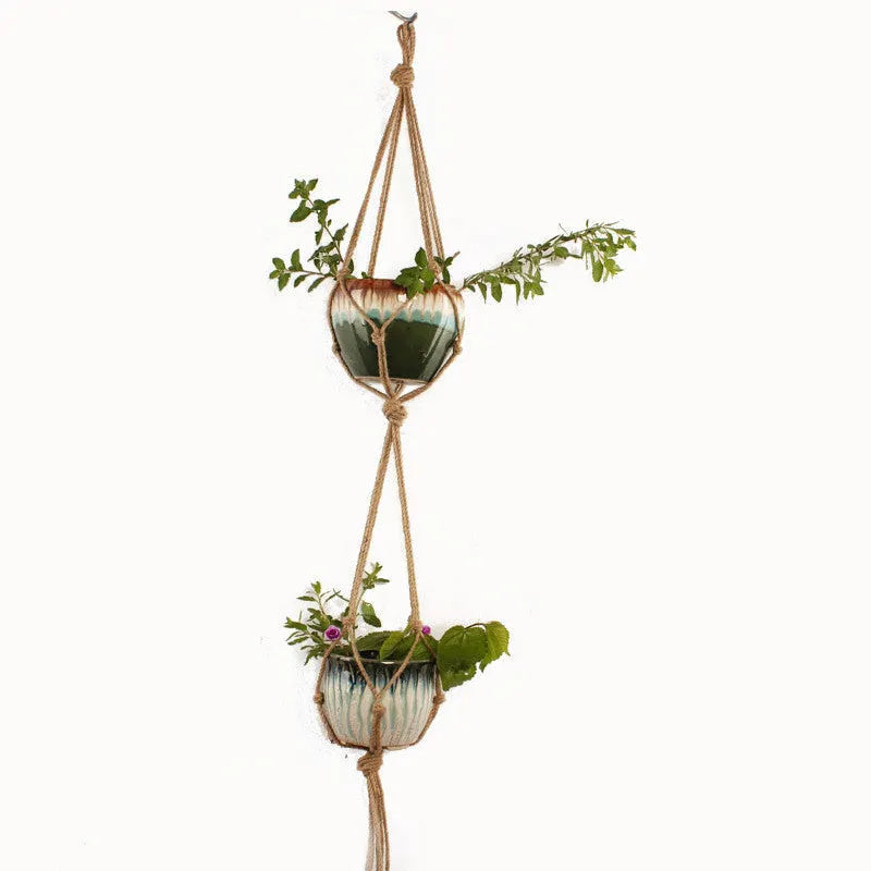 Natural cotton rope woven wall hanging planter holding a small green plant.