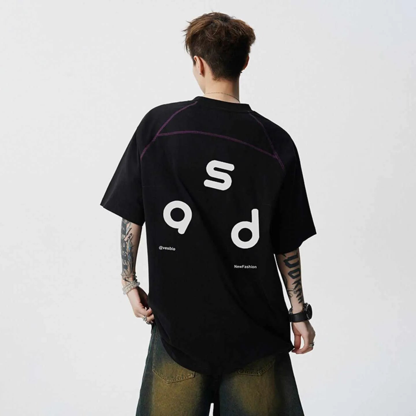 A loose-fitting black cotton short-sleeve T-shirt with a round neck on a hanger.