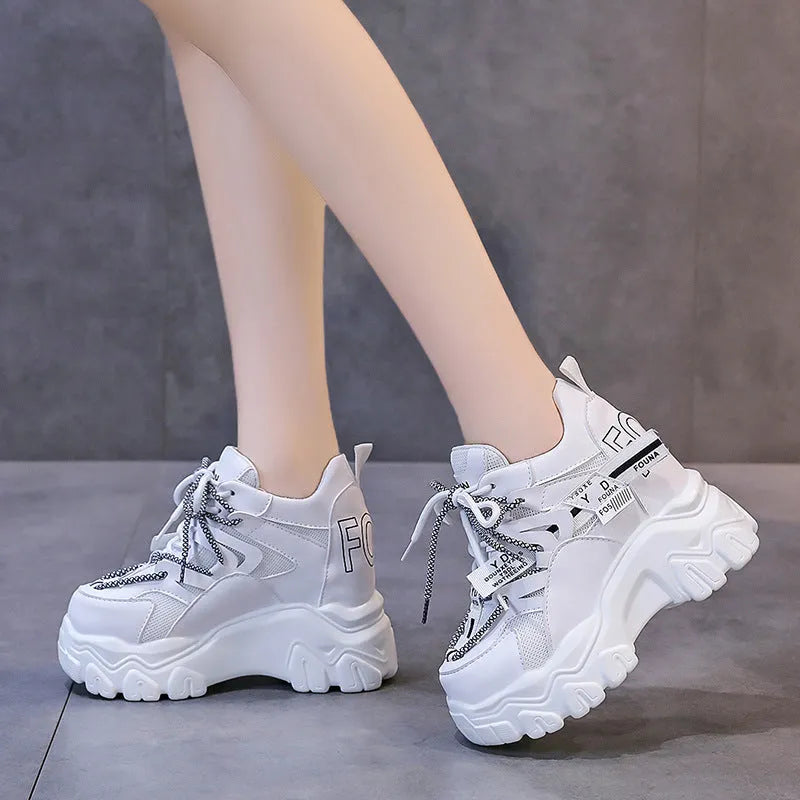 White and black women's mesh platform sports shoes with cross-strap and rubber sole.