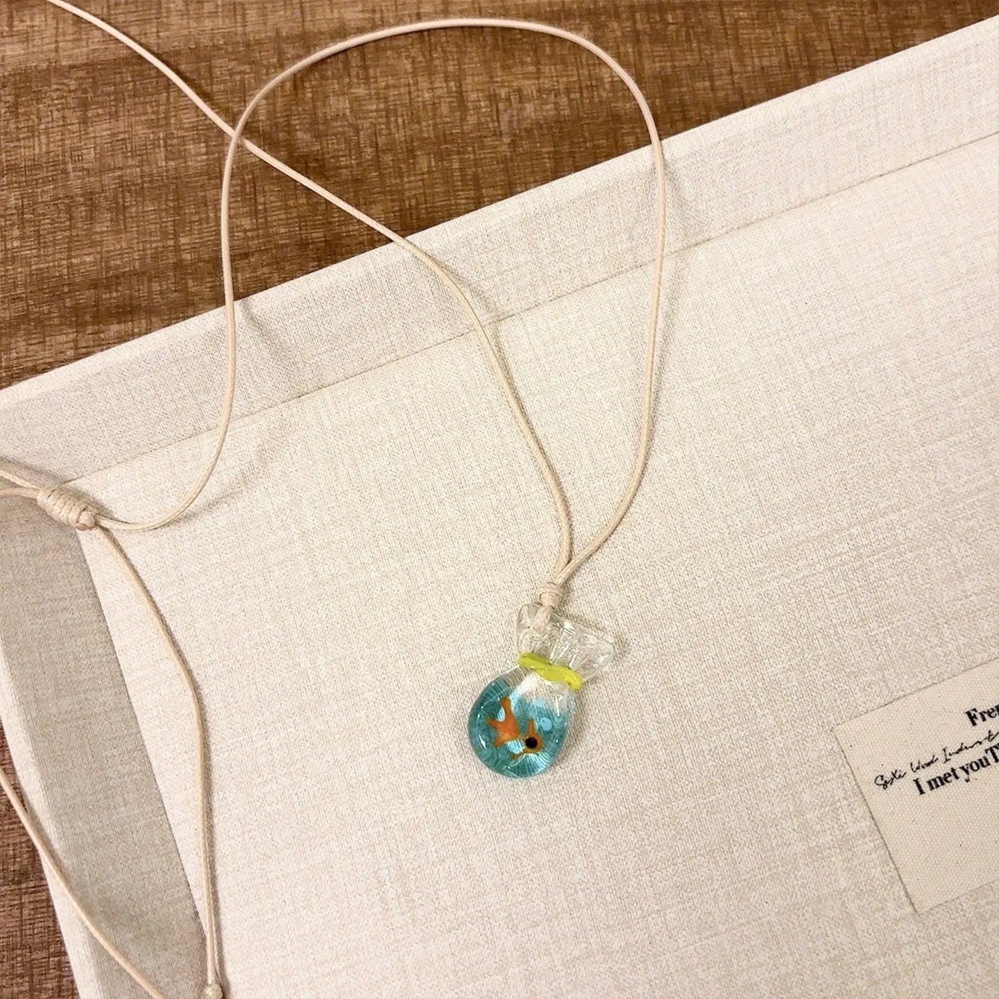 Women's necklace with Small Fish Lucky Bag glaze pendant on a cotton linen chain.