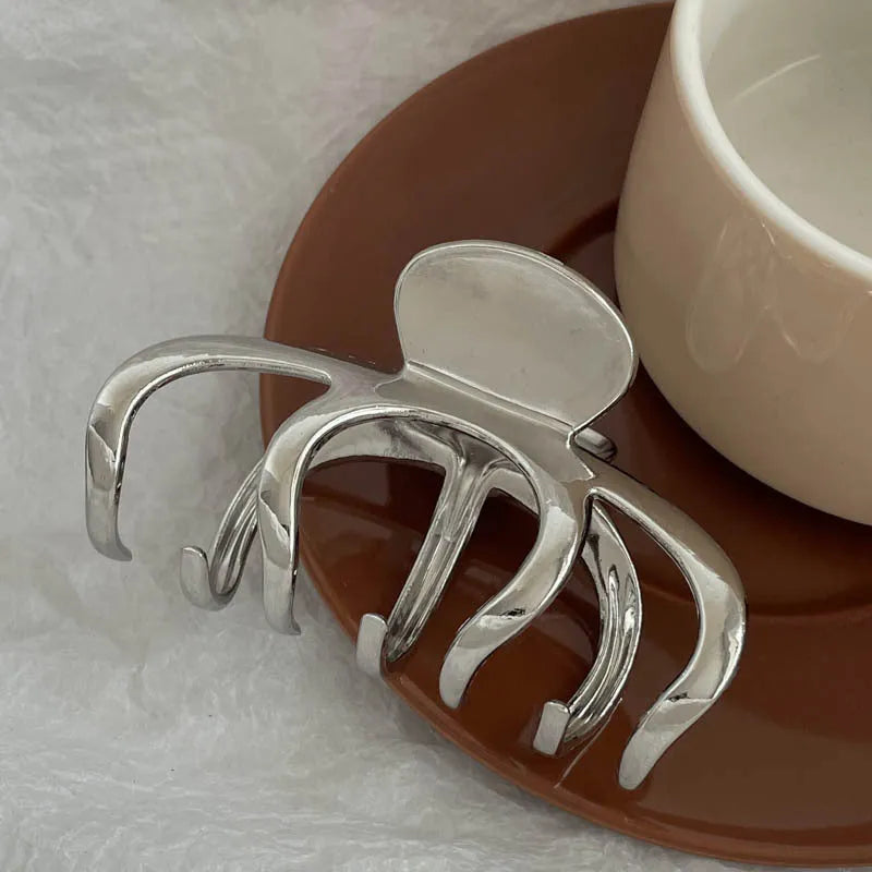 Silver metal hair claw clip assortment showing bows, waves, pearl designs, and geometric shapes from 4cm to 13.5cm