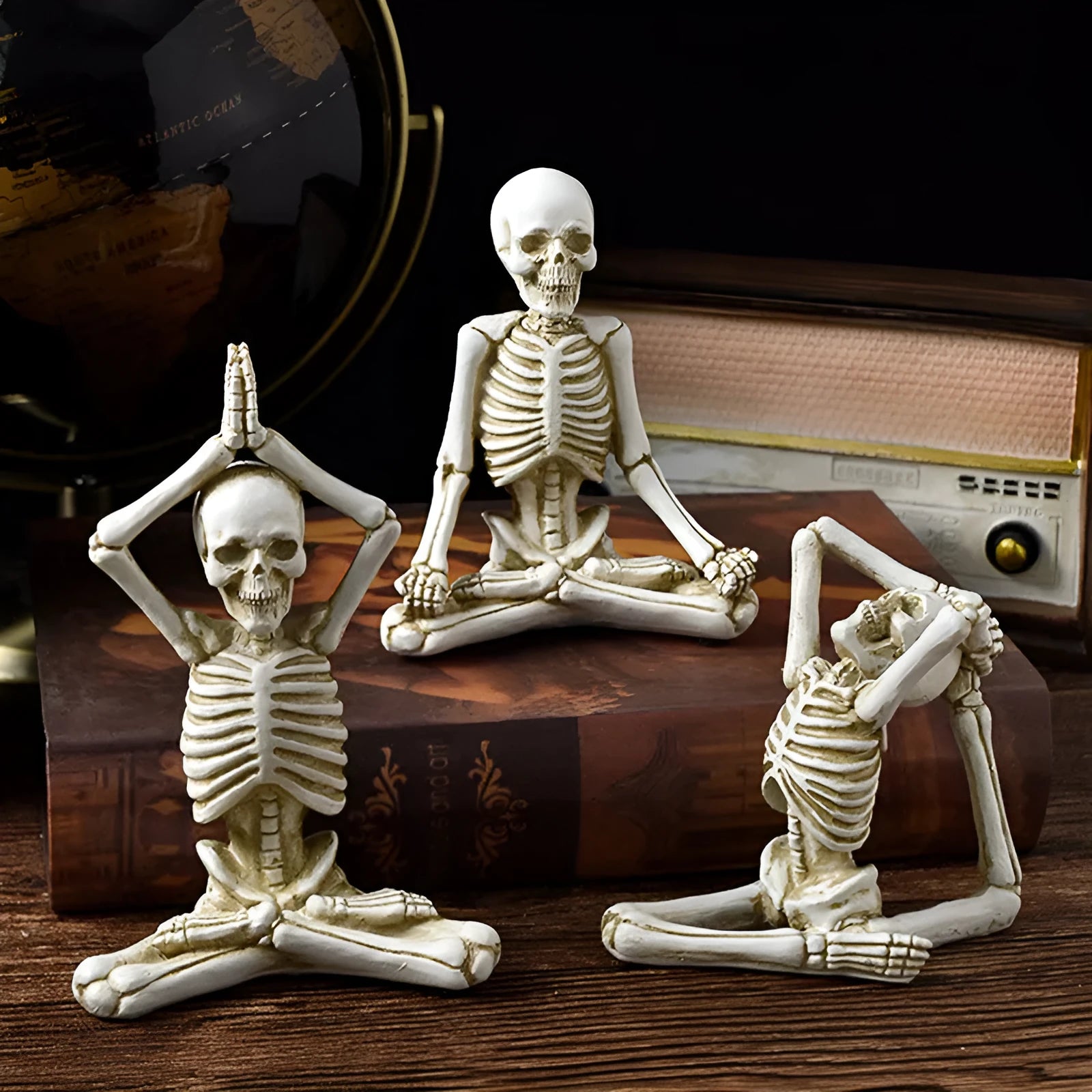 Detailed resin ornament of a yoga pose skeleton skull on a desktop, shown in black and white colour options.