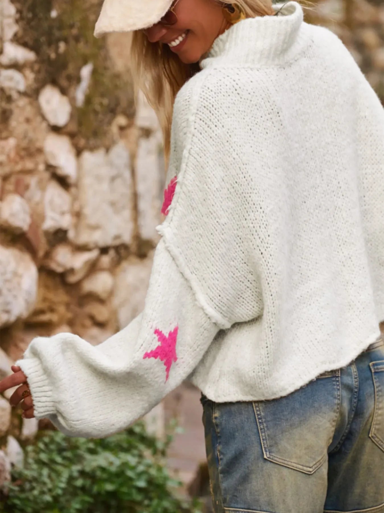 White women's loose turtleneck pullover with a black five-pointed star pattern on the front, made from thick polyester fabric.