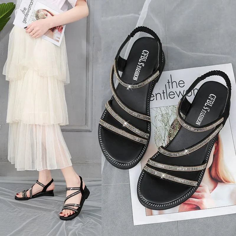 Women's silver flat sandals with rhinestone decoration and elastic strap on a rubber sole.