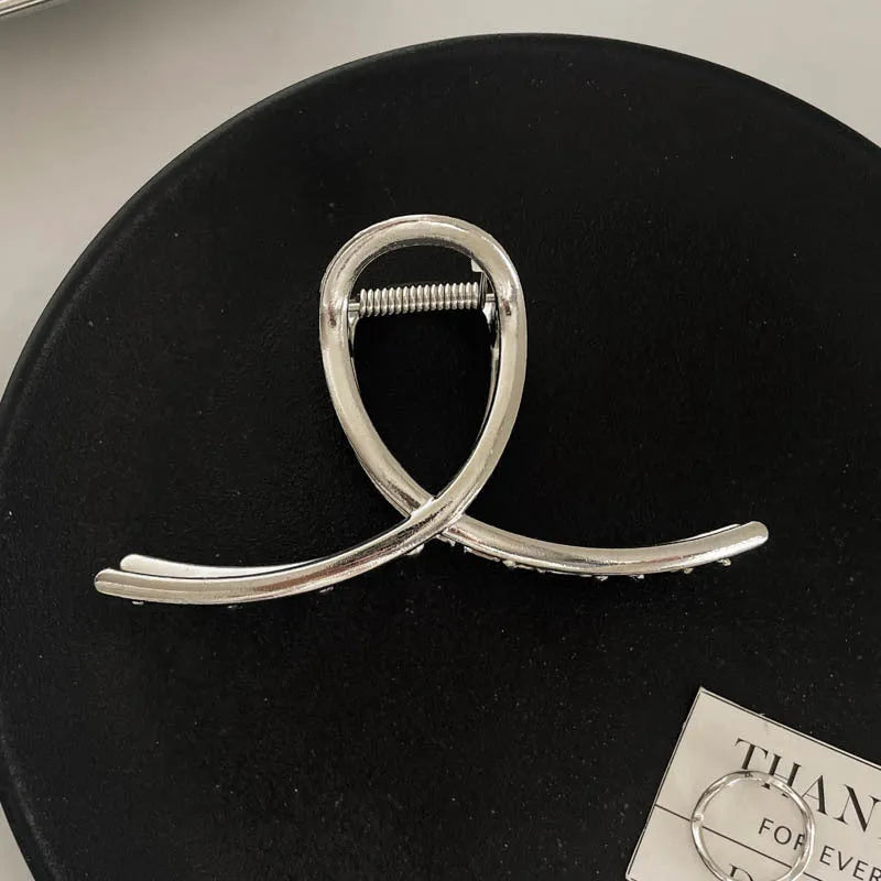 Silver metal hair claw clip assortment showing bows, waves, pearl designs, and geometric shapes from 4cm to 13.5cm