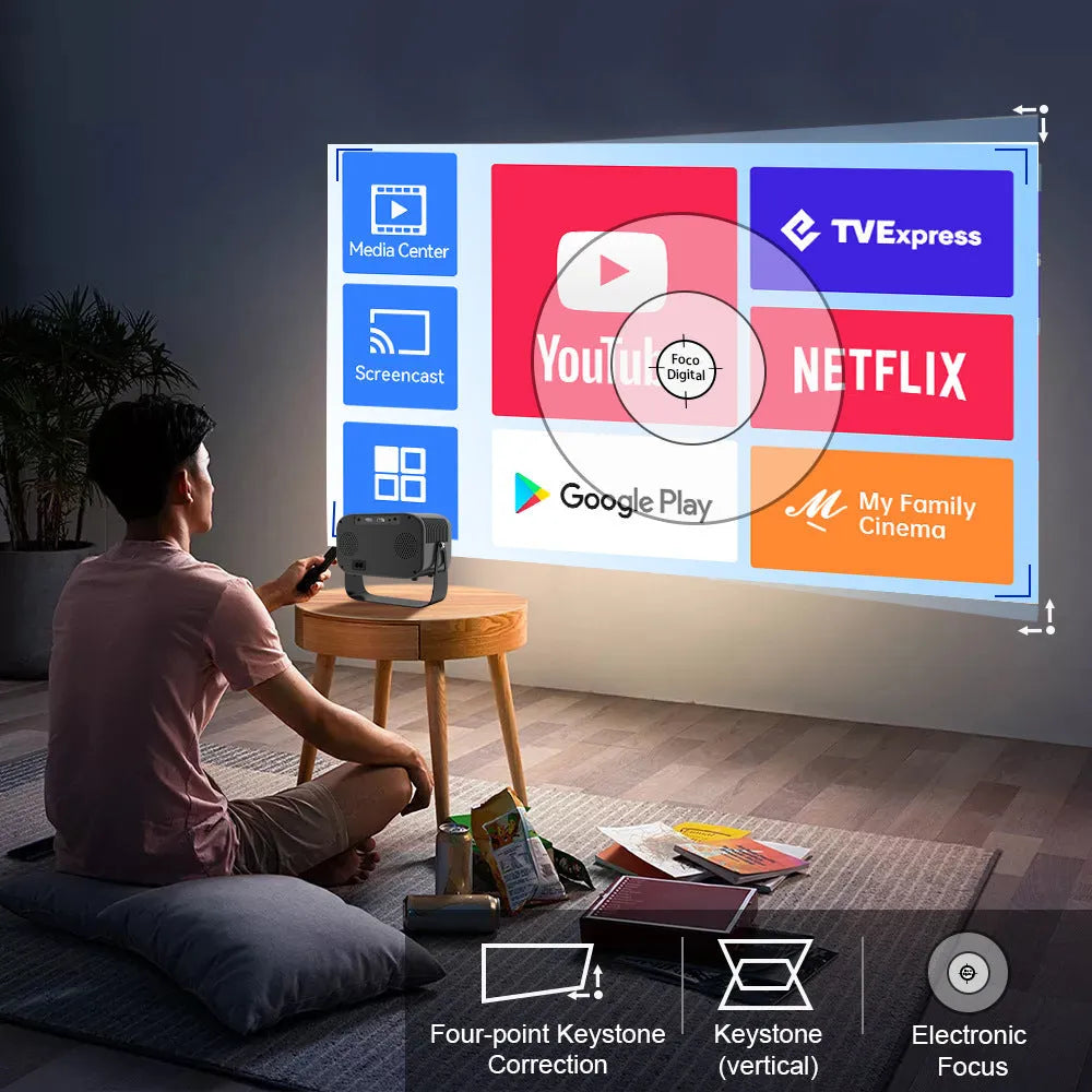 Black HD portable projector with Android system, remote control, and cables on desk