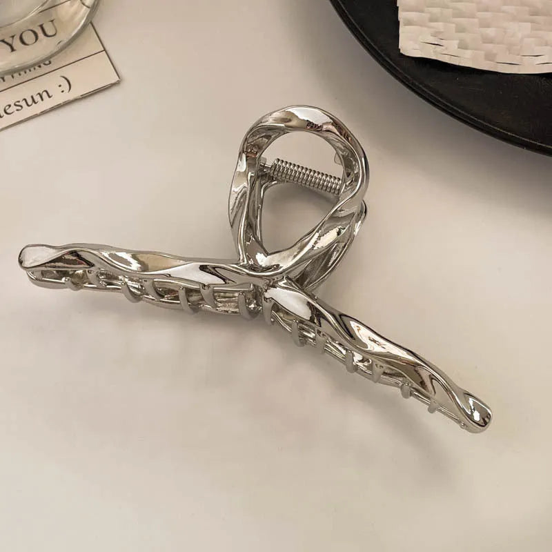Silver metal hair claw clip assortment showing bows, waves, pearl designs, and geometric shapes from 4cm to 13.5cm
