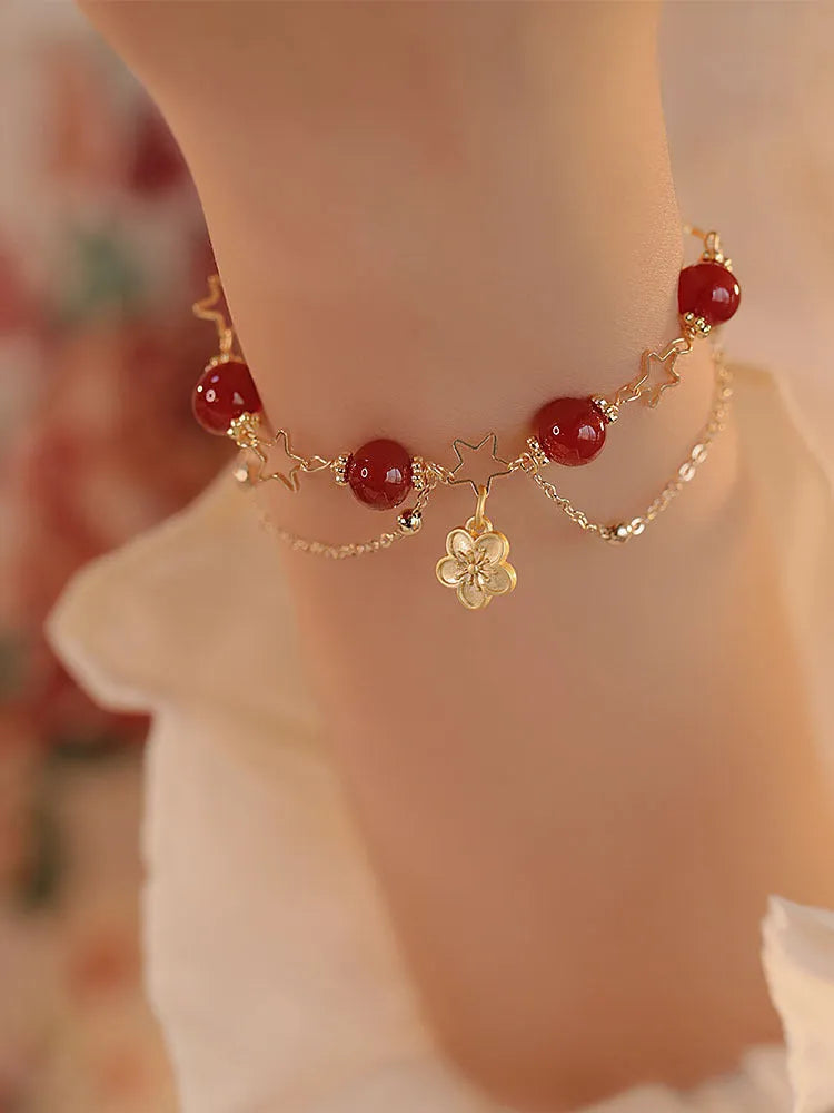 Red agate double layer bracelet with floral and peach blossom charms on a wrist.