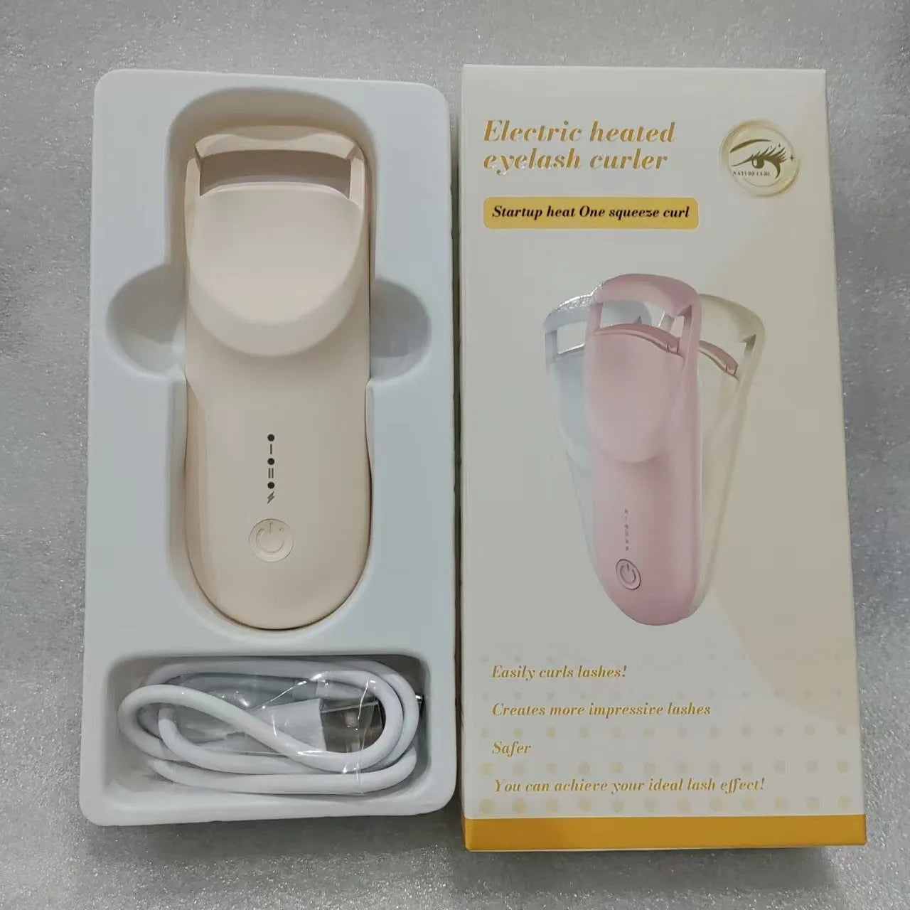 Electric heating eyelash curler in pink with USB charging cable on a white background