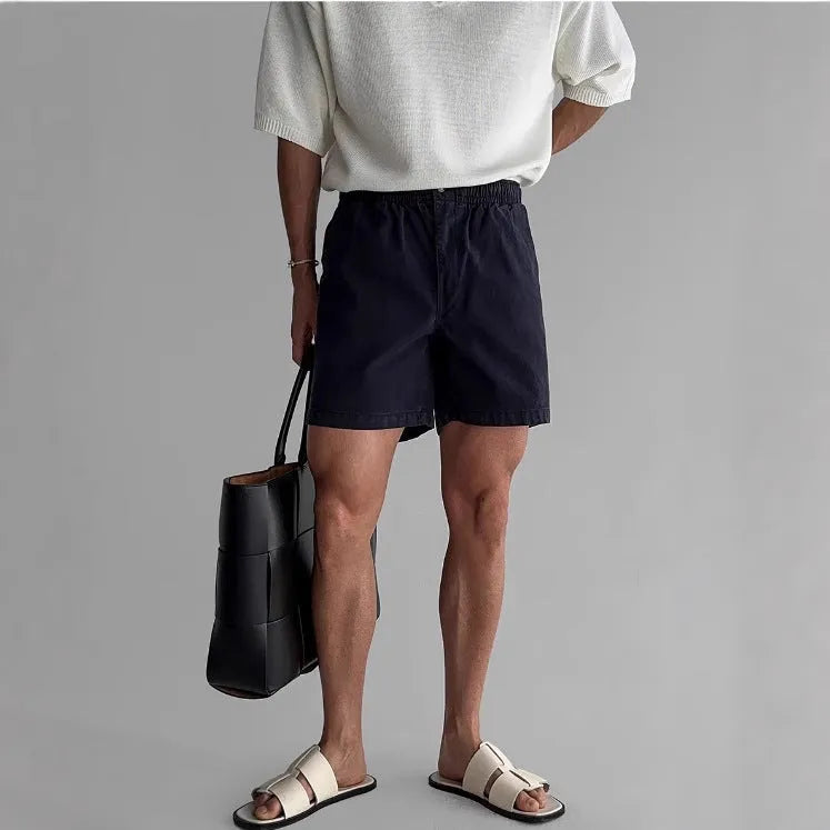 Men's loose-fit cotton sports shorts in black, shown on a hanger.
