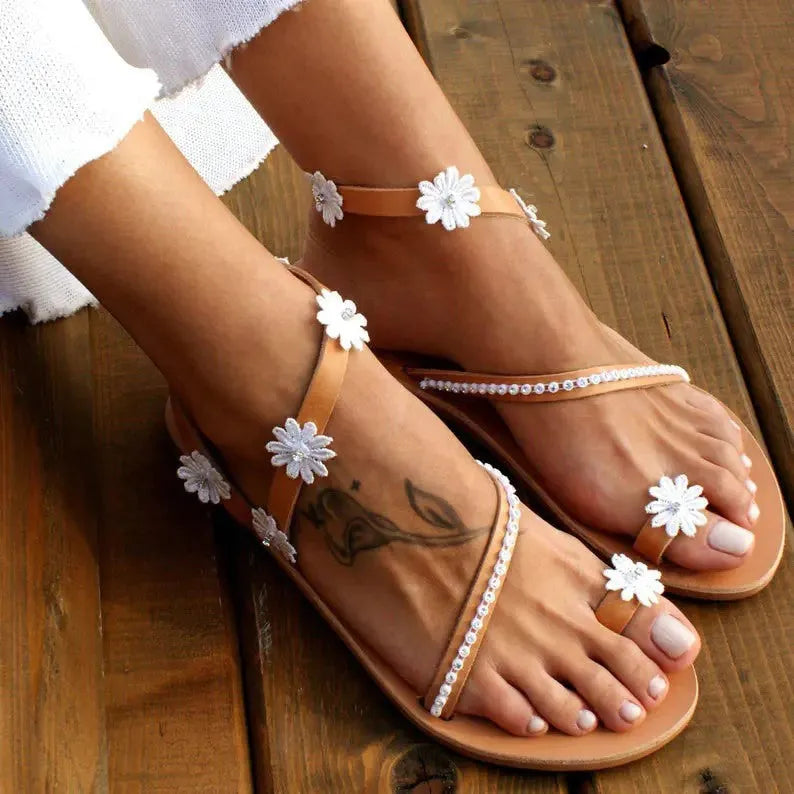 Brown women's flat Roman sandals with a herringbone toe design and ethnic floral pattern on the straps.