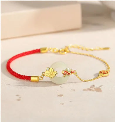 Women's red rope bracelet with silver and gold peace buckle charm featuring koi fish design