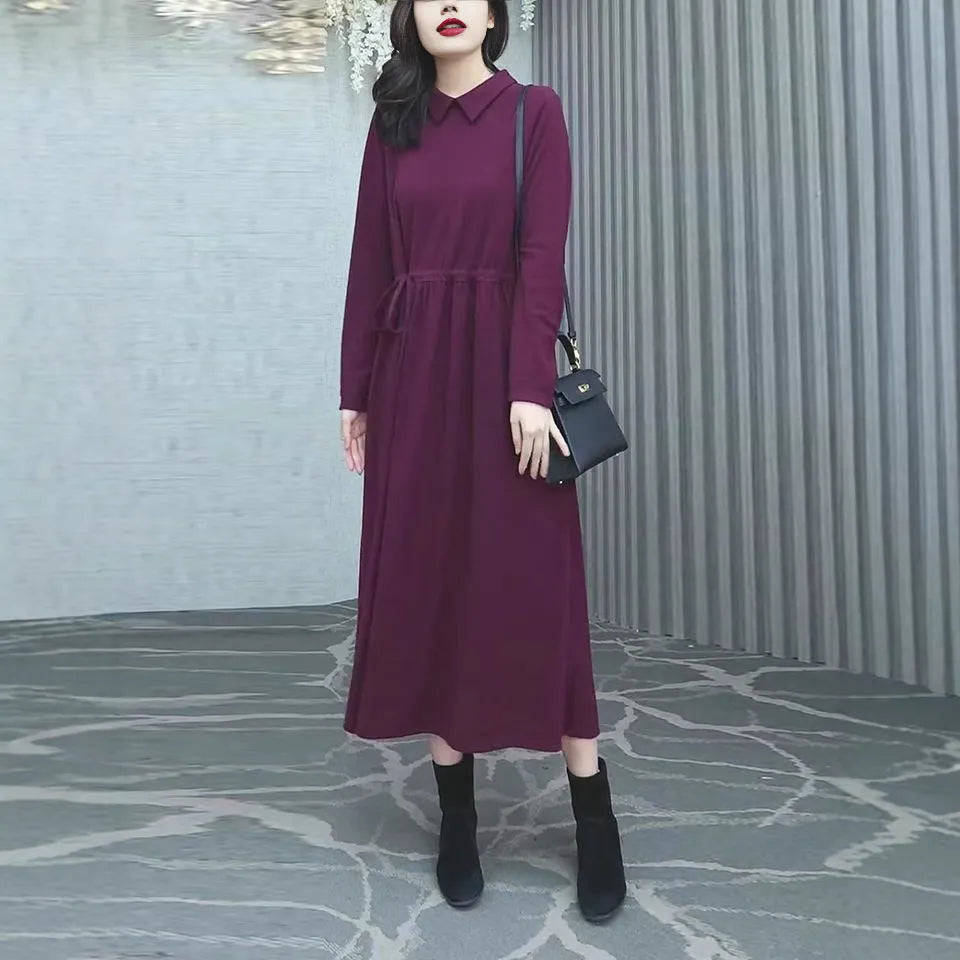 Purplish red plus size long sleeve dress for women with a long skirt, shown on a hanger.