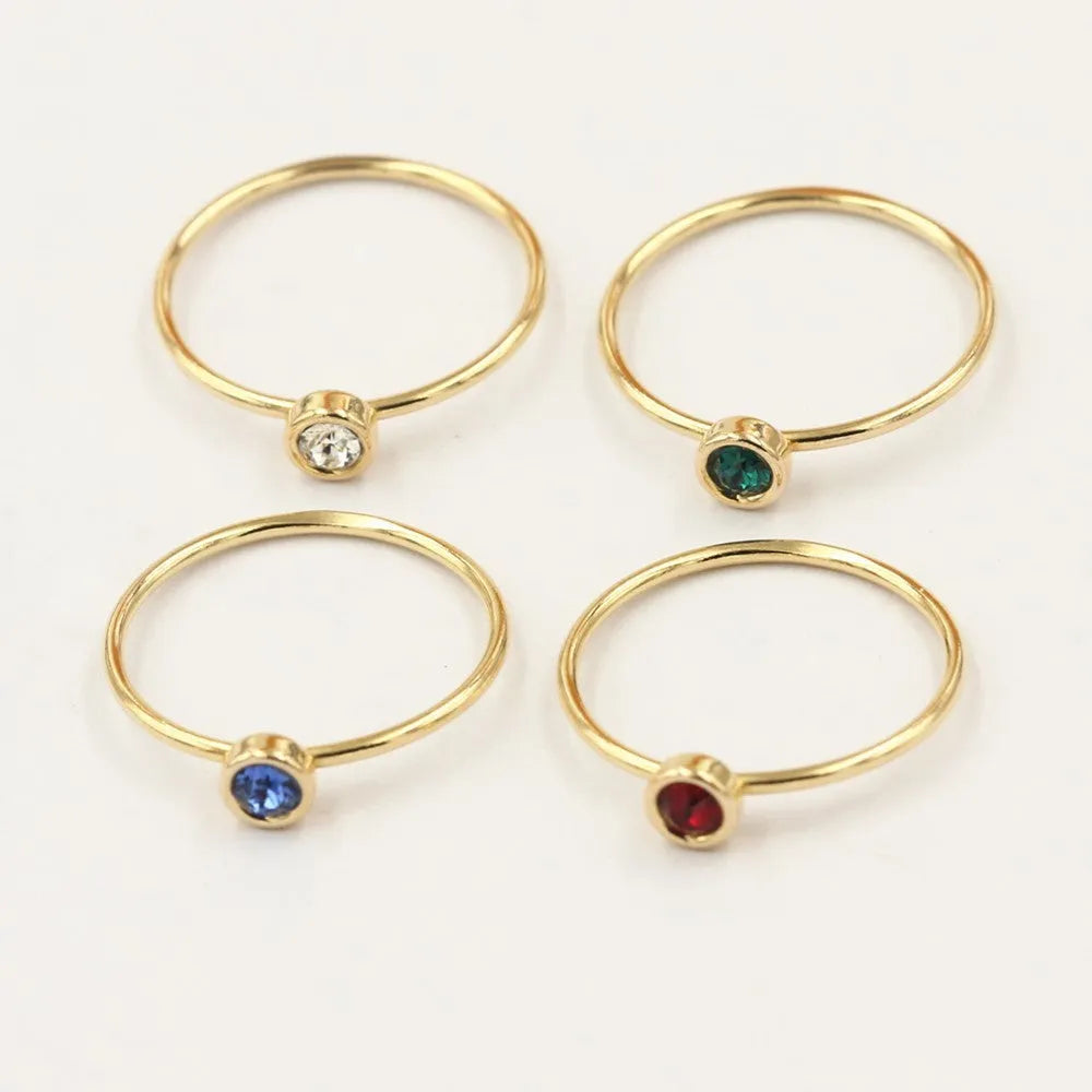 Women's 14K gilded gold-filled zircon copper knuckle ring in green, blue, dark red, or white on a finger.