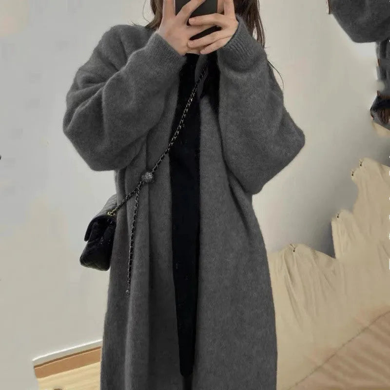 Loose black knitted women's cardigan with a 3D pattern, shown open over a white top.