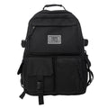 Black and white nylon student backpack with front 3D pockets, shown with laptop in compartment.