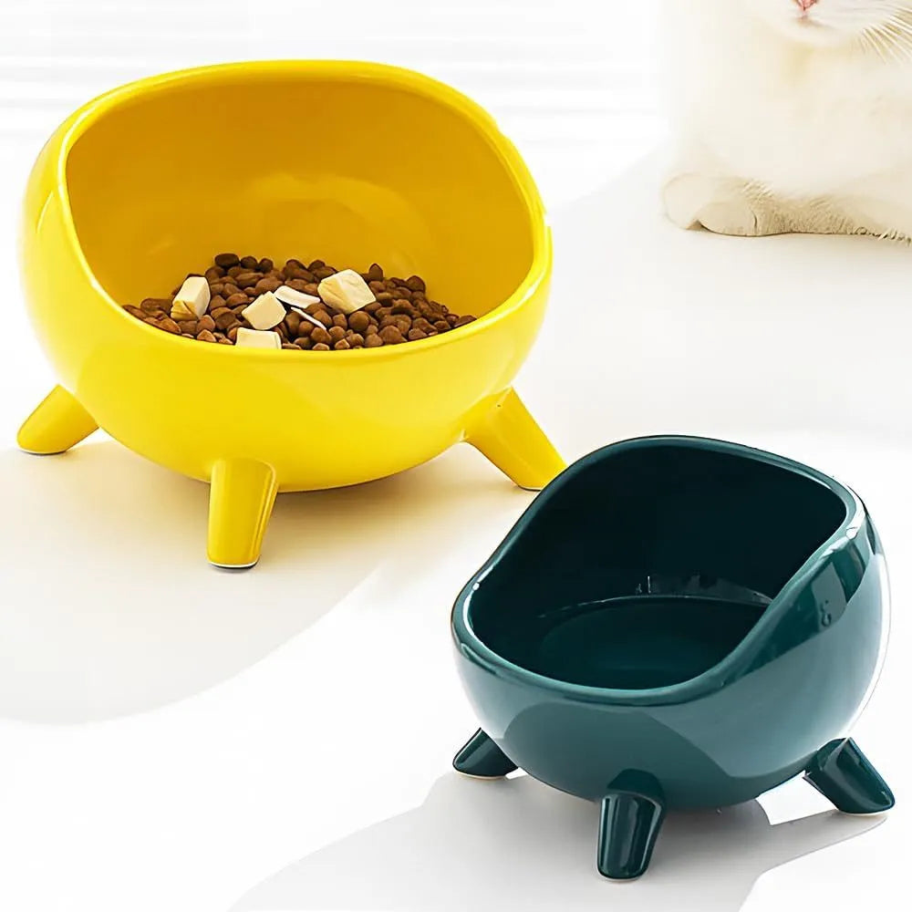 Green ceramic cat food bowl with four legs and rounded arc design on wooden floor