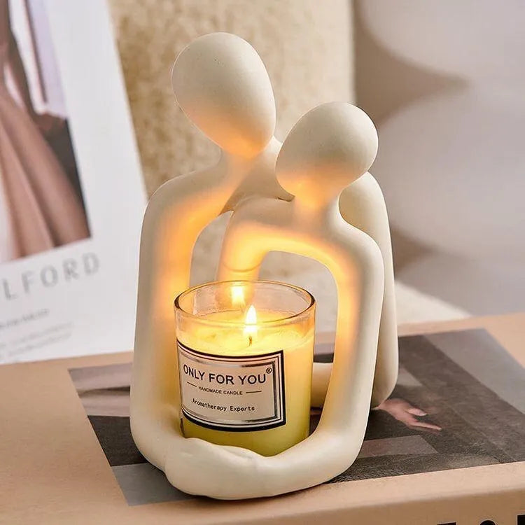 Modern resin statue of an embracing couple in milky white or gold finish on a wooden surface.