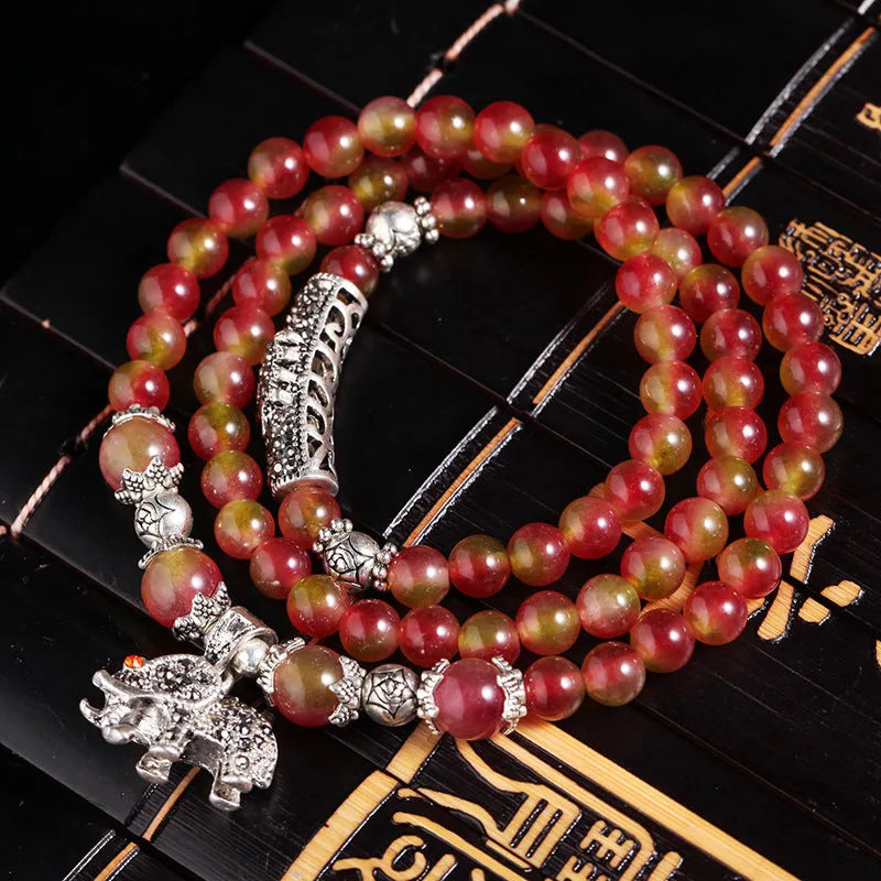 Natural watermelon crystal bracelet with a handmade Chinese knot closure, showing geometric beads.
