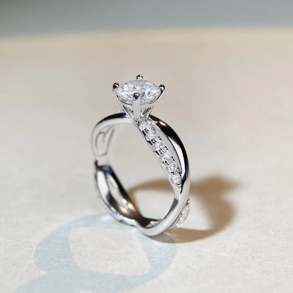 Geometric cross moissanite ring with winding twisted silver arms and four-claw setting