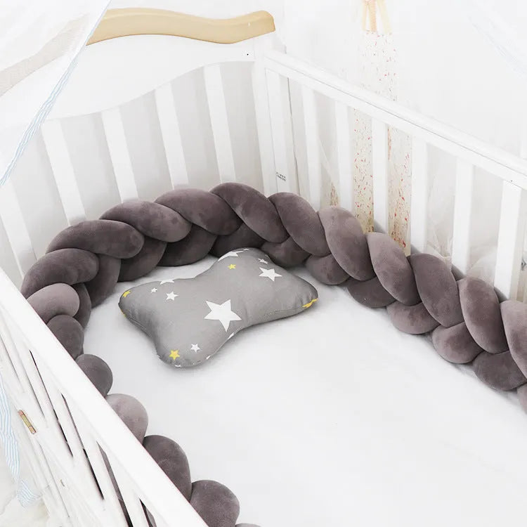 Bendable braid-knot baby crib bumper in spandex velvet, shown in a light grey colour wrapped around a cot.