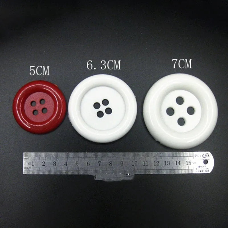 Plastic nylon oversized round button with four holes in various colours and sizes on a white background.