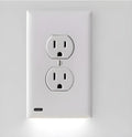 White plug-in LED night light with sensor, installed covering a wall electrical socket.