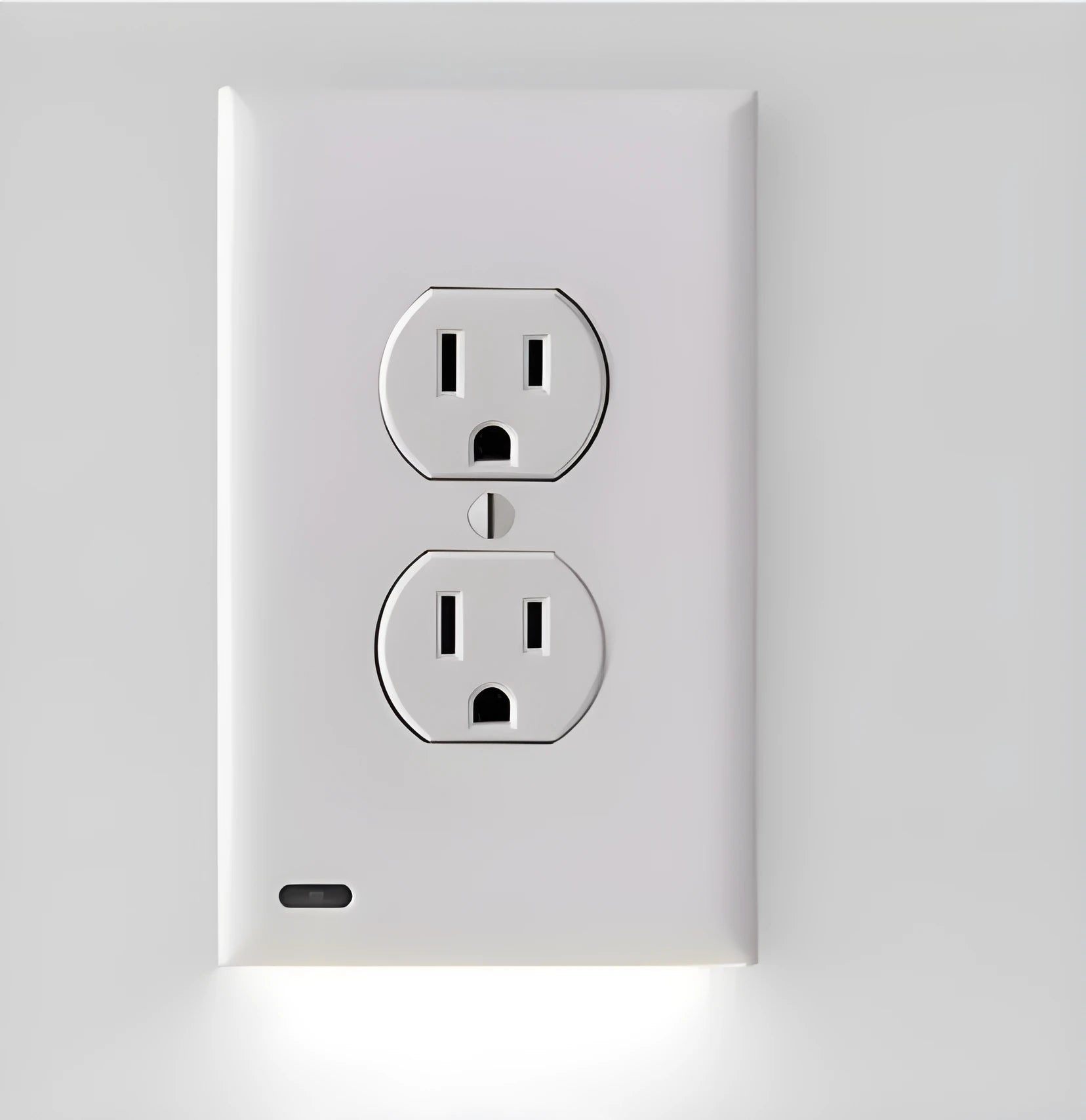 White plug-in LED night light with sensor, installed covering a wall electrical socket.