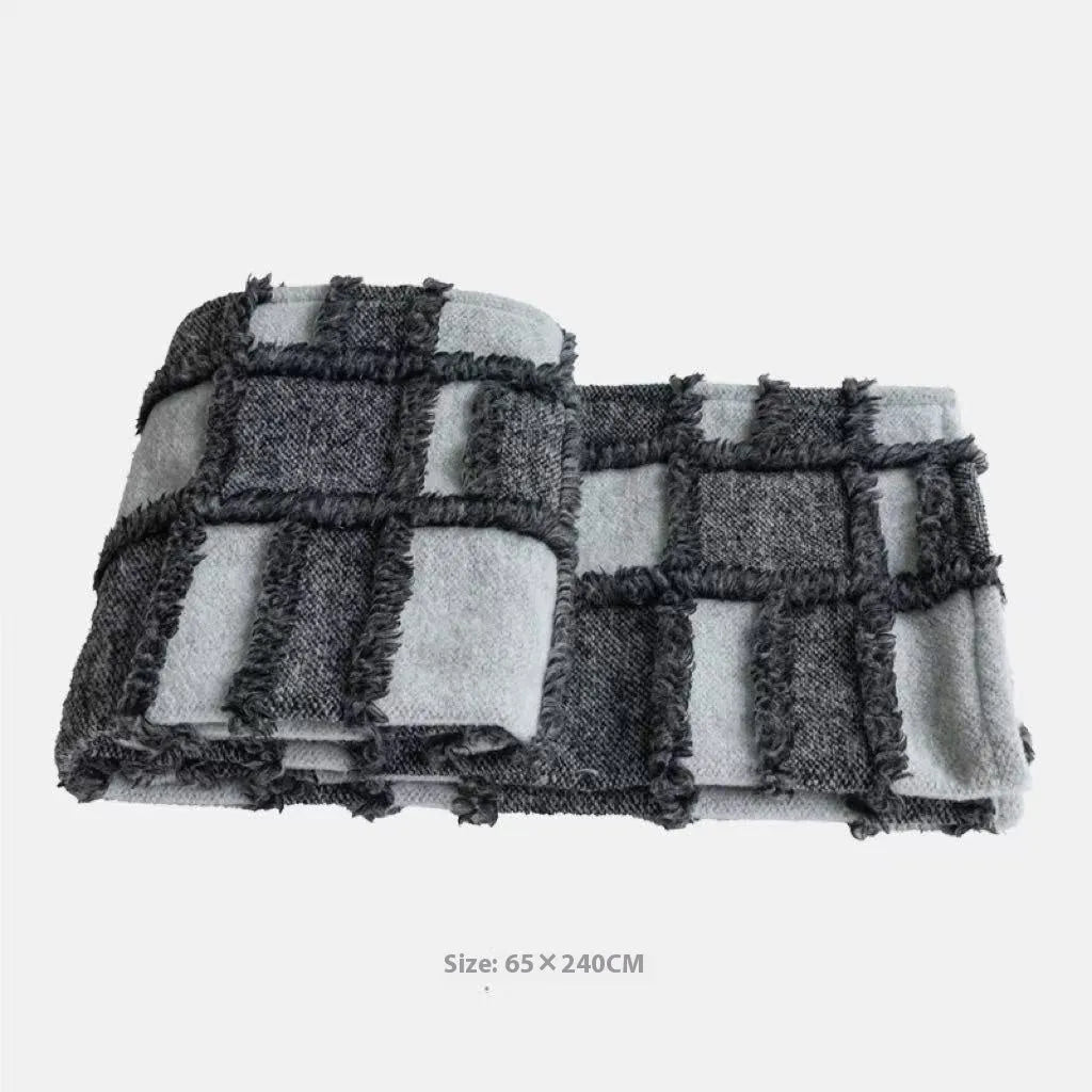 Grey and white plaid polyester bed runner blanket set with matching pillowcase and round leather-look cushion on a bed