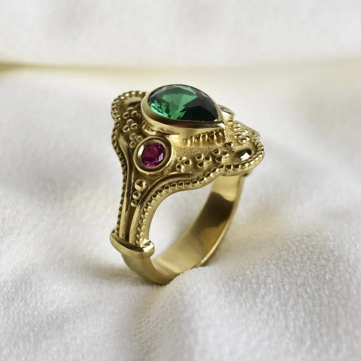 Geometric gold-coloured women's ring with an electroplated finish on a grey background.