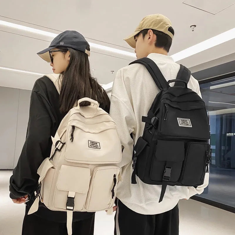 Black and white nylon student backpack with front 3D pockets, shown with laptop in compartment.