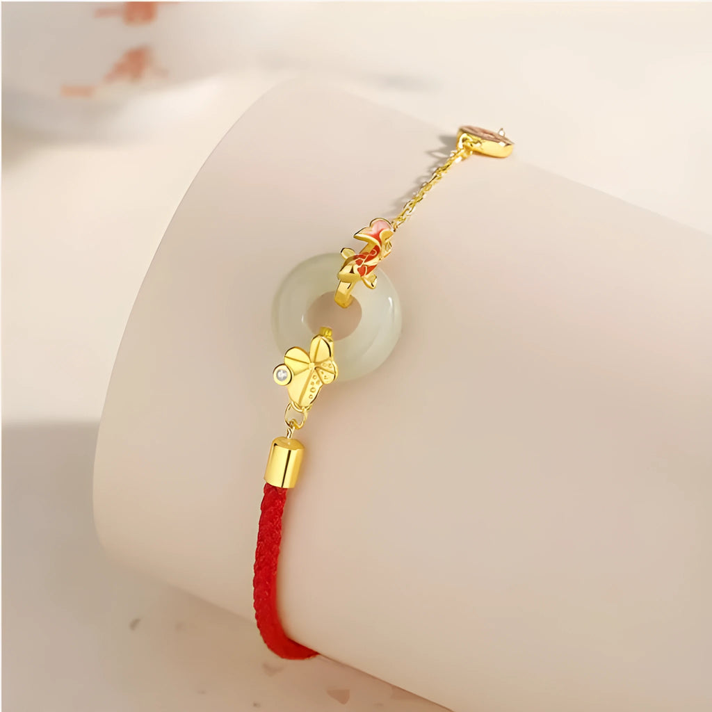 Women's red rope bracelet with silver and gold peace buckle charm featuring koi fish design