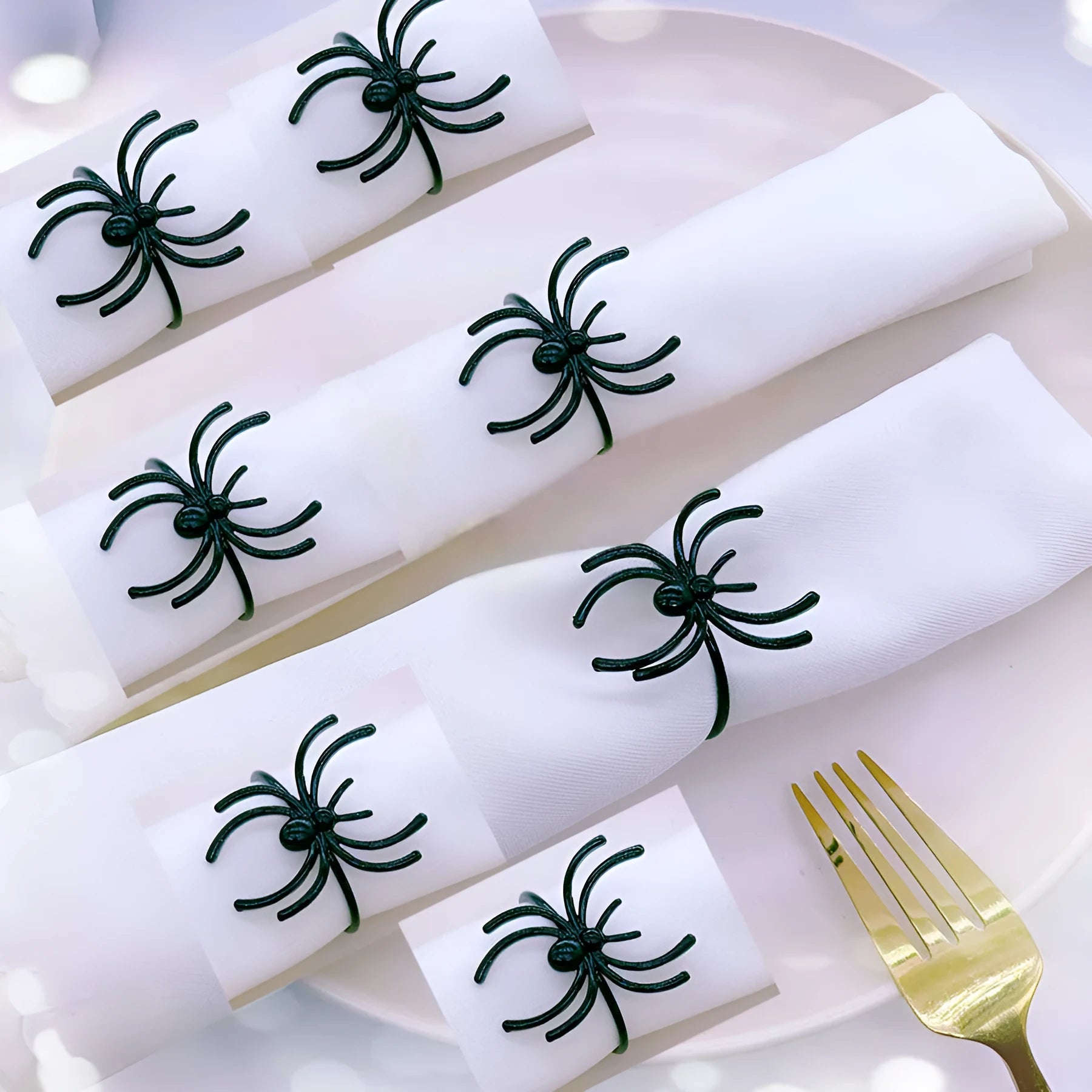 Set of six black alloy napkin rings with spider design for Halloween table decoration.